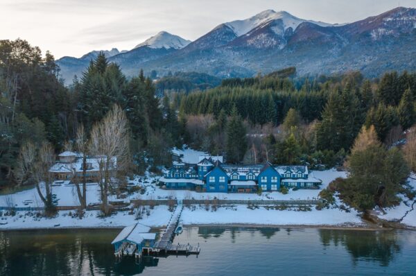 Desde sua criação, em 1988, o Las Balsas mantém sua maneira única de receber os hóspedes. A madeira nobre, as janelas do chão ao teto, que se abrem para a água, e os treze quartos projetados individualmente criam uma atmosfera envolvente e serena, onde tudo é cuidadosamente pensado.O hotel é o primeiro Relais & Châteaux da América Latina, um dos mais importantes selos de turismo de luxo no mundo, recebido já há três décadas. O Las Balsas está às margens do Lago Nahuel Huapi, na Patagônia Argentina, e quem desembarca por ali é movido por uma busca mais emocional do que turística: quer parar, respirar de forma diferente, recapturar o tempo. 
Cada quarto oferece vistas distintas para o lago ou para a floresta, e sua decoração aposta em tecidos suaves, aromas naturais e peças de design escolhidas para acompanhar o silêncio. Alguns se estendem para pequenos terraços privativos; outros se abrem como cabanas sobre palafitas à beira-mar.
A experiência culinária também se torna uma linguagem. O restaurante, administrado por uma equipe comprometida com o meio ambiente e os sabores da estação, trabalha com ingredientes e receitas de origem local que combinam técnica, sensibilidade e raízes patagônicas. De peixes de lago a vegetais colhidos na horta do hotel, cada prato conta a história de um território. Há também petiscos artesanais à beira da lareira, cafés da manhã tranquilos e vinhos escolhidos com conhecimento e carinho.
Culinária sazonal
Nos Las Balsas, o bem-estar não é um serviço: é uma filosofia. Um spa integrado à paisagem oferece momentos de descanso e conexão: piscina aquecida interna e externa, banhos de vapor, terapias corporais com óleos patagônicos e uma sala de relaxamento com vista para a floresta. O corpo encontra seu ritmo em aulas de ioga, sessões de pilates ou caminhadas regenerativas entre árvores centenárias.
A oferta se expande para o exterior com múltiplas maneiras de habitar o ambiente: caiaque ao pôr do sol em Nahuel Huapi, navegação por baías escondidas, trilhas de montanha que partem do jardim do hotel, observação de pássaros, pesca com mosca, ciclismo ou cavalgadas. Tudo é organizado com dedicação, respeito e uma perspectiva pessoal.
Viver a Patagônia
O Las Balsas foi construído com base em uma ética de hospitalidade onde nada é deixado ao acaso. Cada hóspede é recebido como alguém que chega à casa de um amigo, com a elegância tranquila da autenticidade. A equipe local oferece aconchego, conhecimento e uma dedicação ao cuidado que transforma a estadia em uma lembrança preciosa.
Desde 2021, o Las Balsas possui a certificação B Corp, um reconhecimento internacional que celebra empresas que atendem a altos padrões de desempenho socioambiental, transparência e responsabilidade. 
Com apoio Madre Travel
