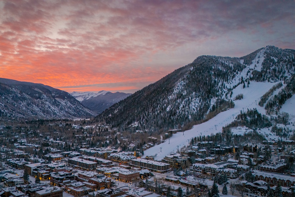Vista aérea de Aspen em direção a Independence Pass durante o nascer do sol, incluindo o exterior do The Little Nell e o teleférico Silver Queen.